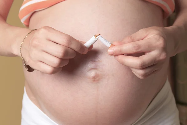 Mujer embarazada joven sosteniendo cigarrillo en la habitación del bebé —  Fotos de Stock