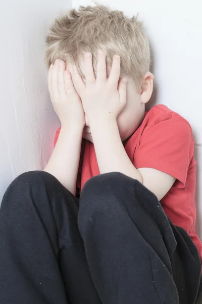Одинокий ребенок, прислонившийся к стене — стоковое фото