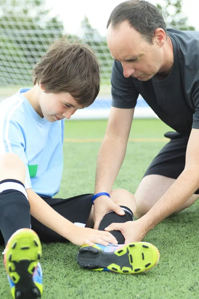 En ung fotballspiller med ball på banen. – stockfoto