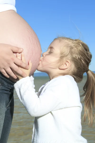 En glad gravid kvinde udenfor med er barn - Stock-foto