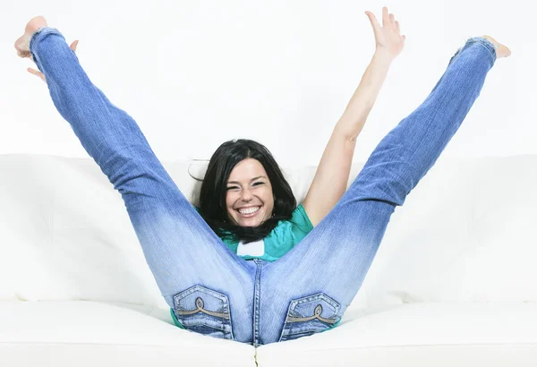 Uma bela mulher sorridente relaxando no sofá — Fotografia de Stock