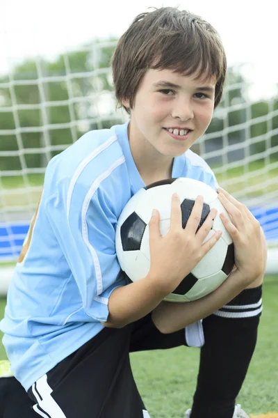 Unga fotbollspelare med bollen på fältet — Stockfoto