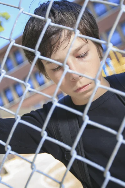 Triste garçon sur un terrain de jeu de l'école fermeture — Photo