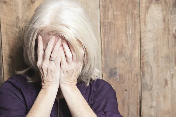 Depress senior person with wood background — Stock Photo, Image