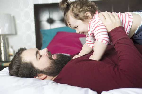 Retrato de un padre joven y feliz con un bebé en la cama en casa — Foto de Stock