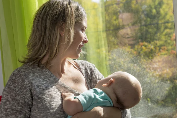 Mamma med barn står vid fönstret — Stockfoto