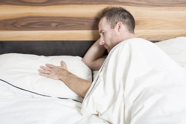 Tiro brilhante de homem chateado jaz na cama — Fotografia de Stock