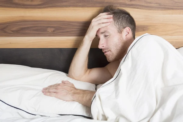 Tiro brilhante de homem chateado jaz na cama — Fotografia de Stock