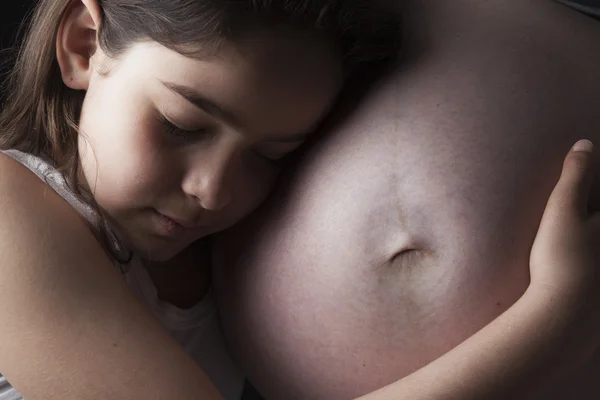 Hermosa niña pequeña abrazando a las madres embarazadas —  Fotos de Stock