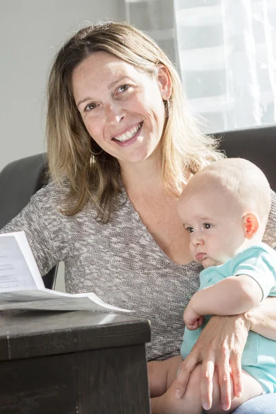 Mère tenant bébé et tapant sur ordinateur portable dans la cuisine . — Photo