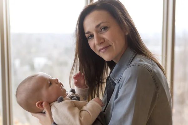 Mother with her baby at home close to  window — Stock Photo, Image