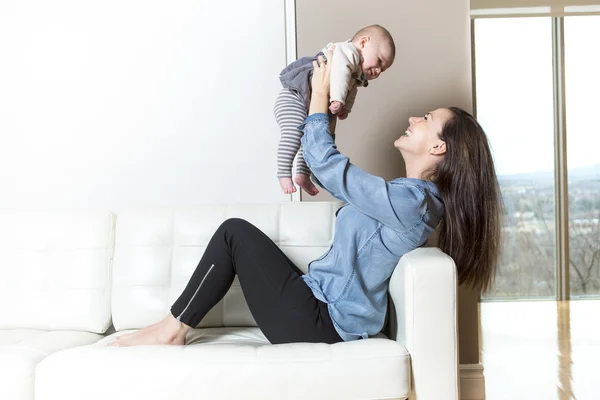 Mother with baby on the sofa taking good time — Stock Photo, Image