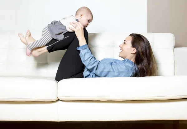 Mãe com bebê no sofá tomando bom tempo — Fotografia de Stock