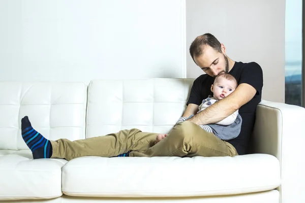 父亲抱着婴儿坐在沙发上 — 图库照片