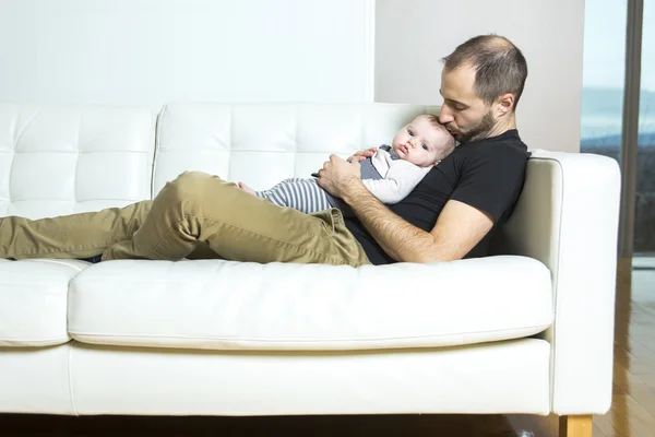 父亲抱着婴儿在沙发上好时间 — 图库照片