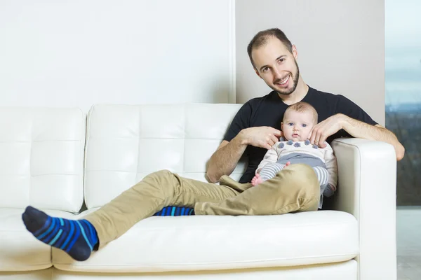 父亲抱着婴儿坐在沙发上 — 图库照片