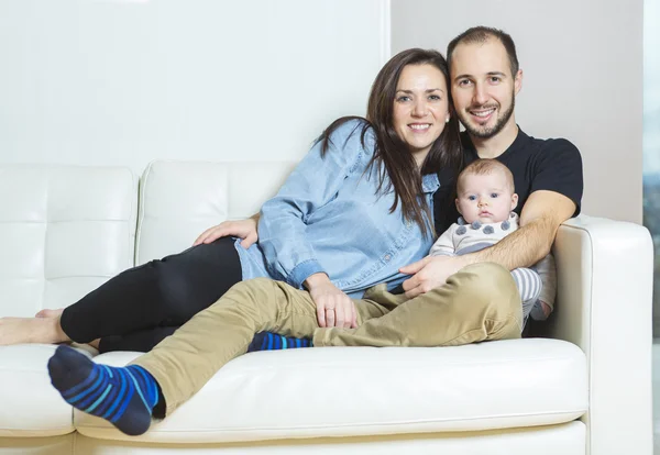 Guapo joven padre y madre con lindo bebé recién nacido en el sofá — Foto de Stock