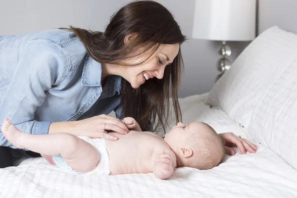 Anne ile bebek yatakta eğleniyor — Stok fotoğraf