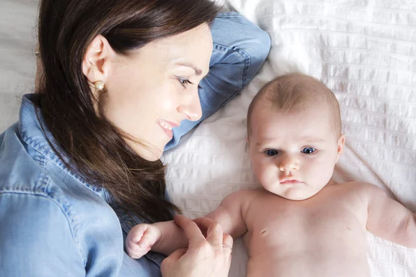 Bebê e mãe na cama branca tendo bom tempo — Fotografia de Stock