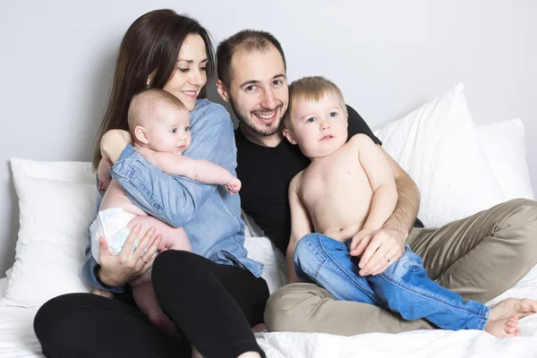 Счастливая семья на белой кровати в спальне — стоковое фото