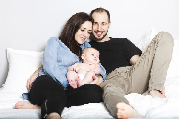 Los padres cariñosos con su linda niña en la cama — Foto de Stock