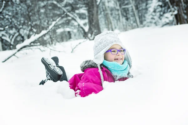 Маленькая девочка играет со снегом на улице зимой — стоковое фото