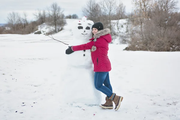 Снеговик и молодая девушка в зимний сезон — стоковое фото