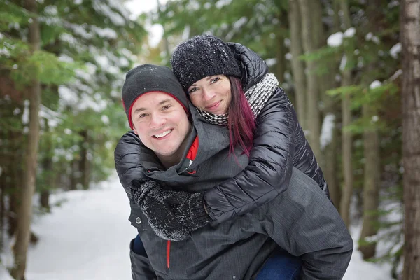 Pareja de invierno a cuestas en la nieve sonriendo feliz y emocionado . — Foto de Stock