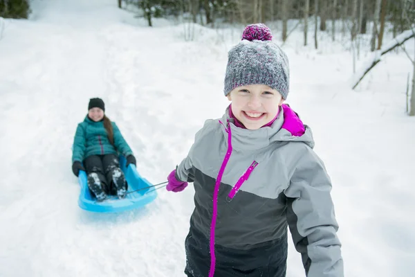 Los niños tirando de trineo a través de paisaje nevado — Foto de Stock