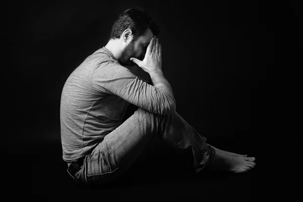 Low key portrait of man sitting in dark and contemplating — Stock Photo, Image