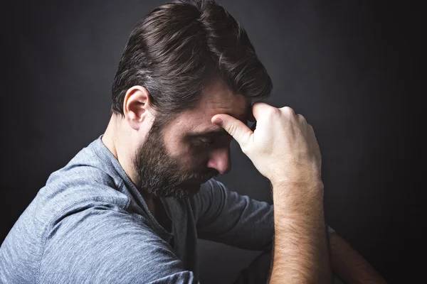 Low key portrait of man sitting in dark and contemplating — Stock Photo, Image