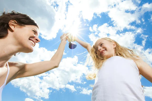 Happy mother and daughter holding a trophy high up — Stock Photo, Image