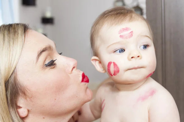 Мама целует своего ребенка, зашивает портреты — стоковое фото