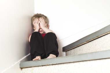 Neglected lonely child leaning at the wall clipart