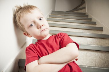 Neglected lonely child leaning at the wall clipart