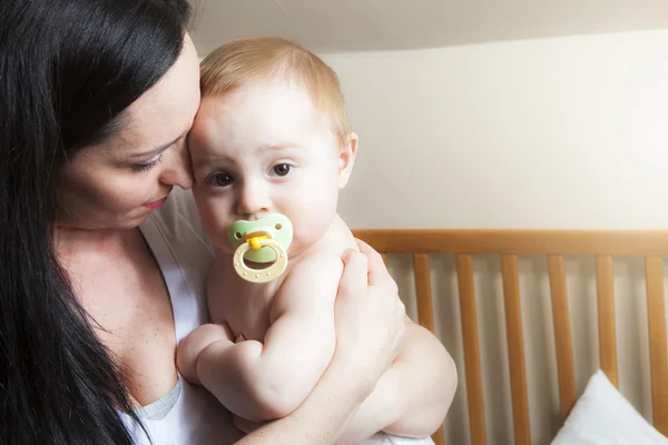 Devoted mother laying son down into crib for nap in bedroom — Stock Photo, Image