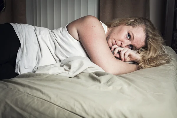En kvinne blir kvalm av å ligge på senga. – stockfoto