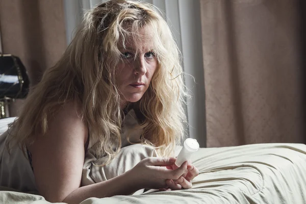 Una mujer triste tomando medicamentos en la cama . — Foto de Stock