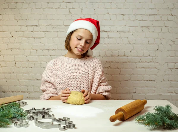 Різдвяне печиво випічка, мила дівчина-підліток у різдвяному капелюсі робить тісто для різдвяного печива на кухні — стокове фото