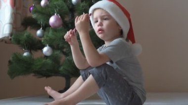 Noel Baba şapkalı küçük çocuk Noel şekeri yiyor.