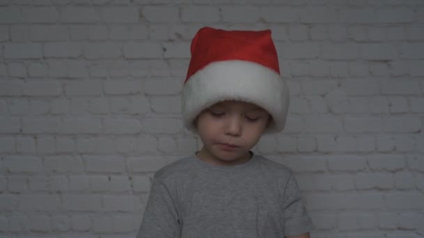 Kleine jongen met kerstmuts die kerstsuikerriet eet — Stockvideo