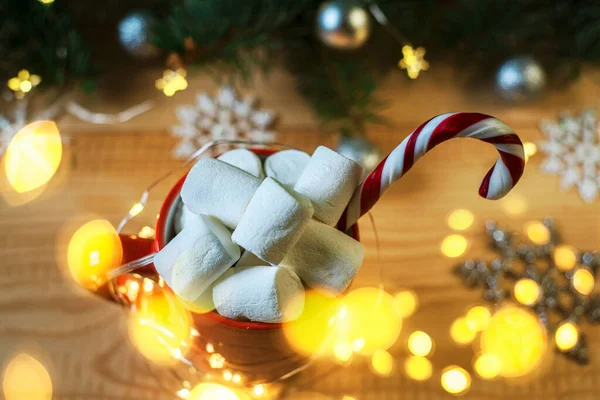 Christmas marshmallow cup with candy cane and Christmas lights on the foreground — Stock Photo, Image