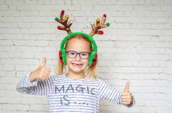 Happy girl wearing Christmas raindeer horns and eyeglasses with her thumbs up, poor eyesight correction — Stock Photo, Image