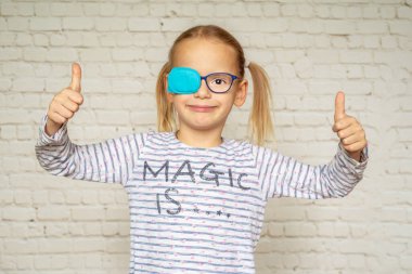 Little girl wearing occluder with her thumbs up, treatment of amblyopia and poor eyesight clipart