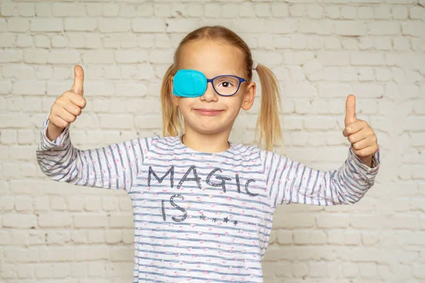 Little girl wearing occluder with her thumbs up, treatment of amblyopia and poor eyesight — Stock Photo, Image