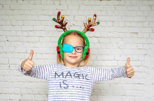 Маленька дівчинка в окулярах і рогах для різдвяних оленів, лікування амбліопії та поганого зору — стокове фото