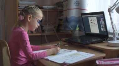 İnternette okuyan ve bilgisayarını evde kullanan göz gazlı küçük bir kız.