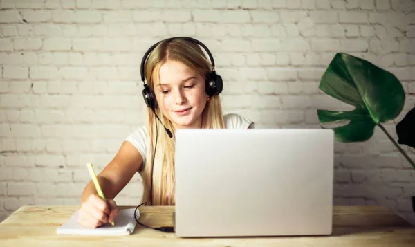 Çocuklar evde eğitim görüyor, kulaklıklı genç bir kız evde internetten okuyor, e-öğrenim kavramı geliştiriyor.