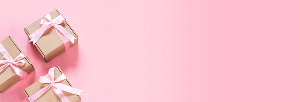 Caja de regalo con lazo de cinta rosa sobre fondo rosa, banner del día de San Valentín —  Fotos de Stock