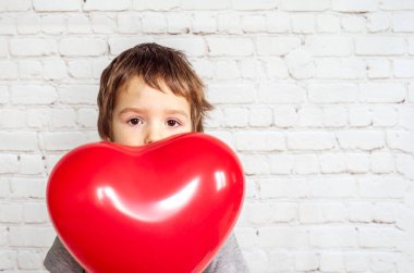 Kırmızı kalpli küçük bir çocuk, sevgililer günü geçmişi olan bir balon.